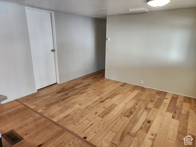 Interior space featuring light-toned wood-finish flooring, smooth wall paneling, and a flush-mount ceiling light fixture