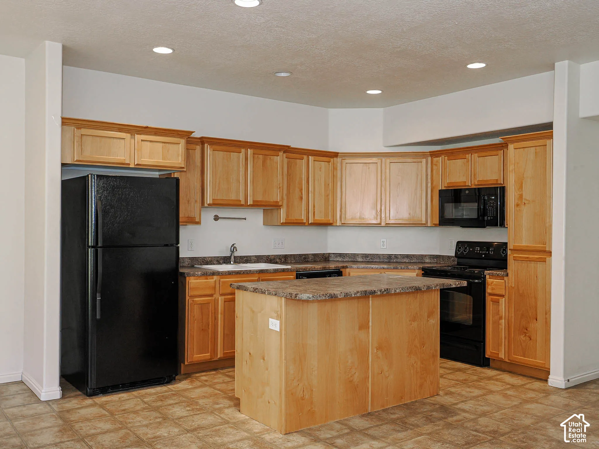 Kitchen featuring light-finish wood cabinetry, a central island with countertop, stone-pattern laminate countertops, and recessed ceiling lighting
