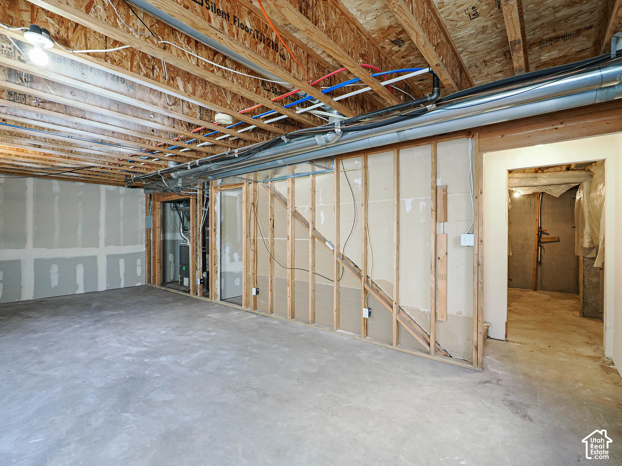 Unfinished interior space featuring exposed wood joist ceilings, concrete flooring, exposed wall framing, and mechanical system access
