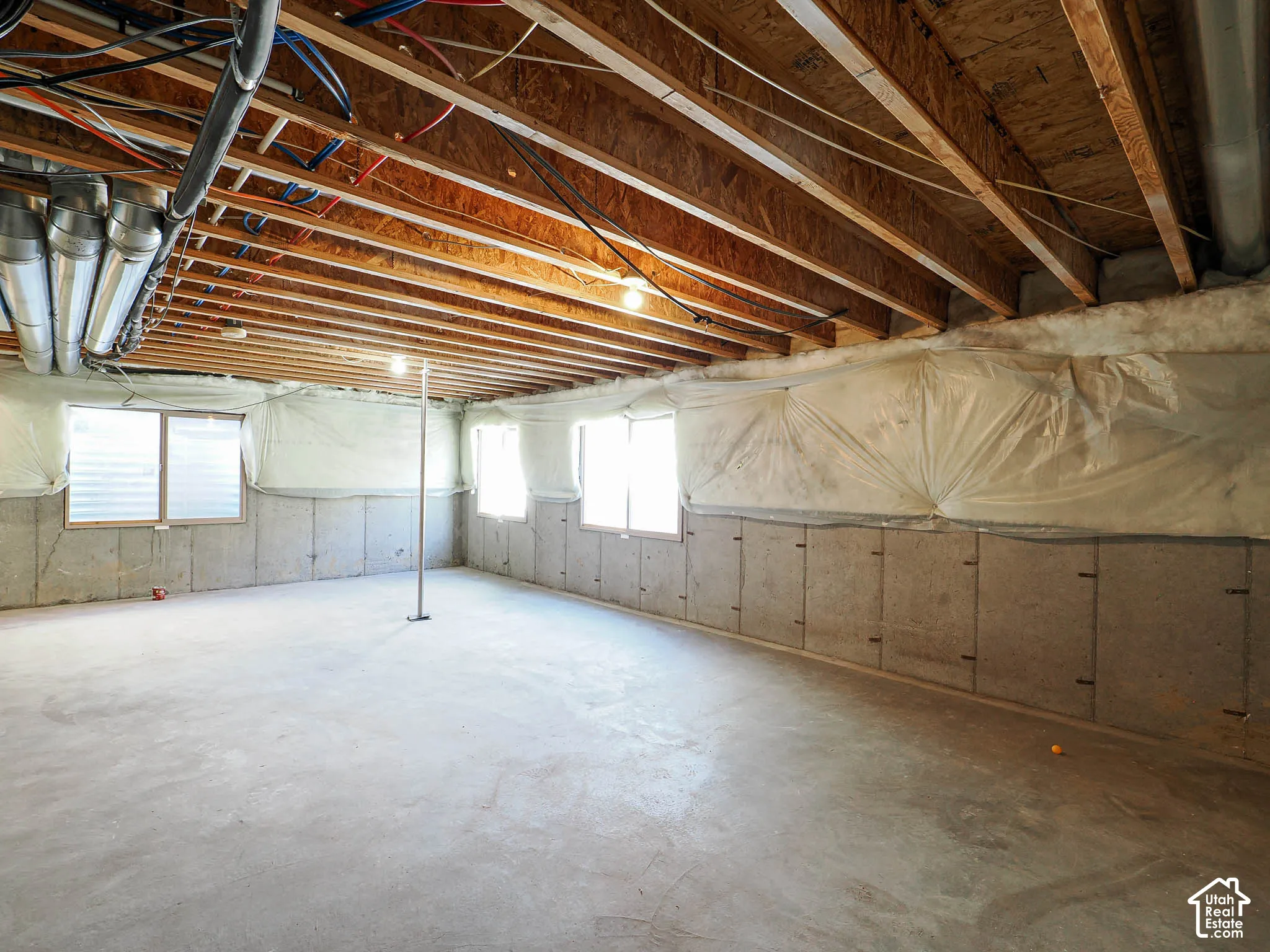 Unfinished lower level featuring exposed wood joist ceilings, concrete flooring, concrete foundation walls, and multiple egress windows