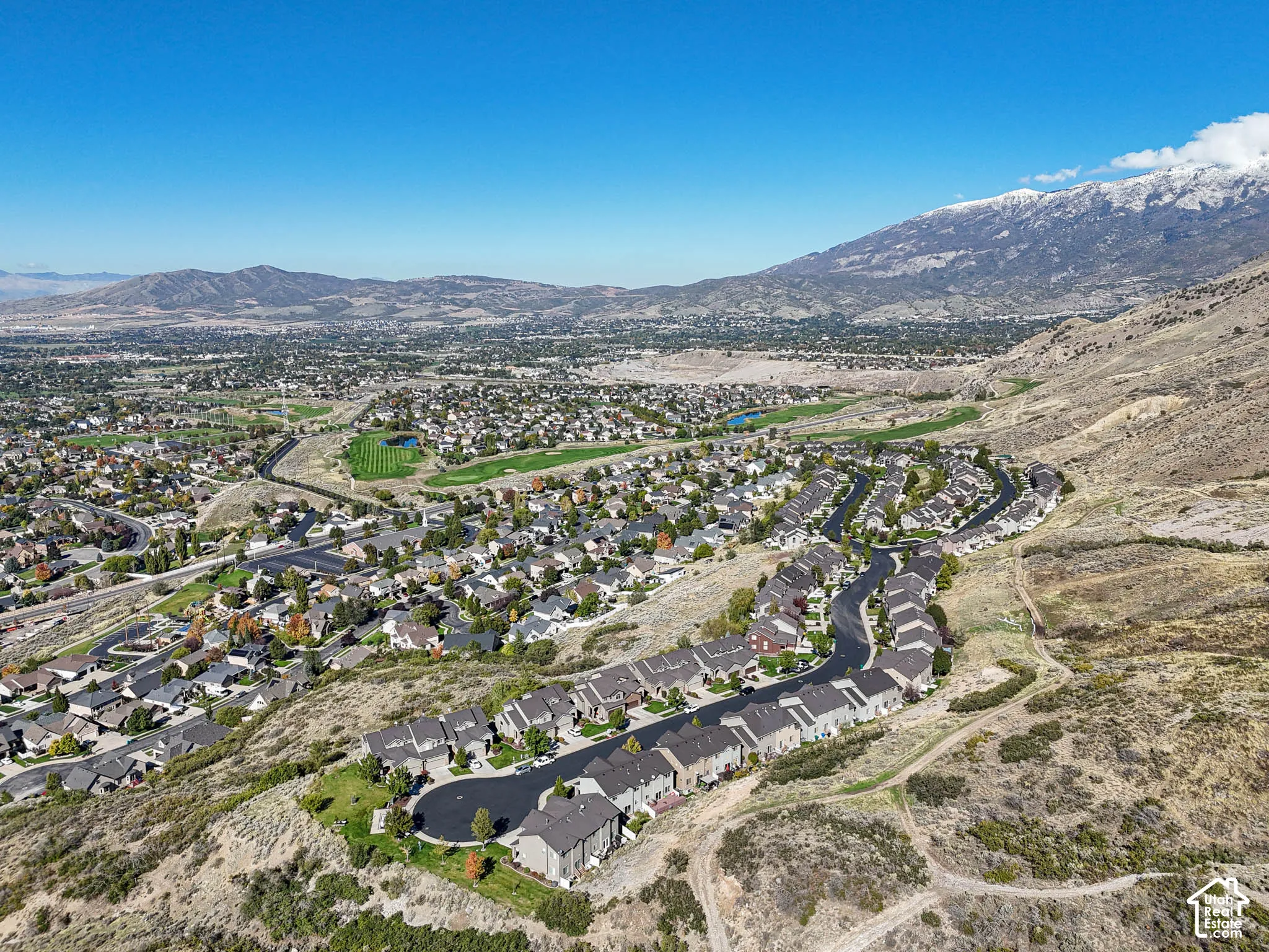 Aerial perspective showcasing mountain range backdrop, expansive valley landscape, and paved hillside street network