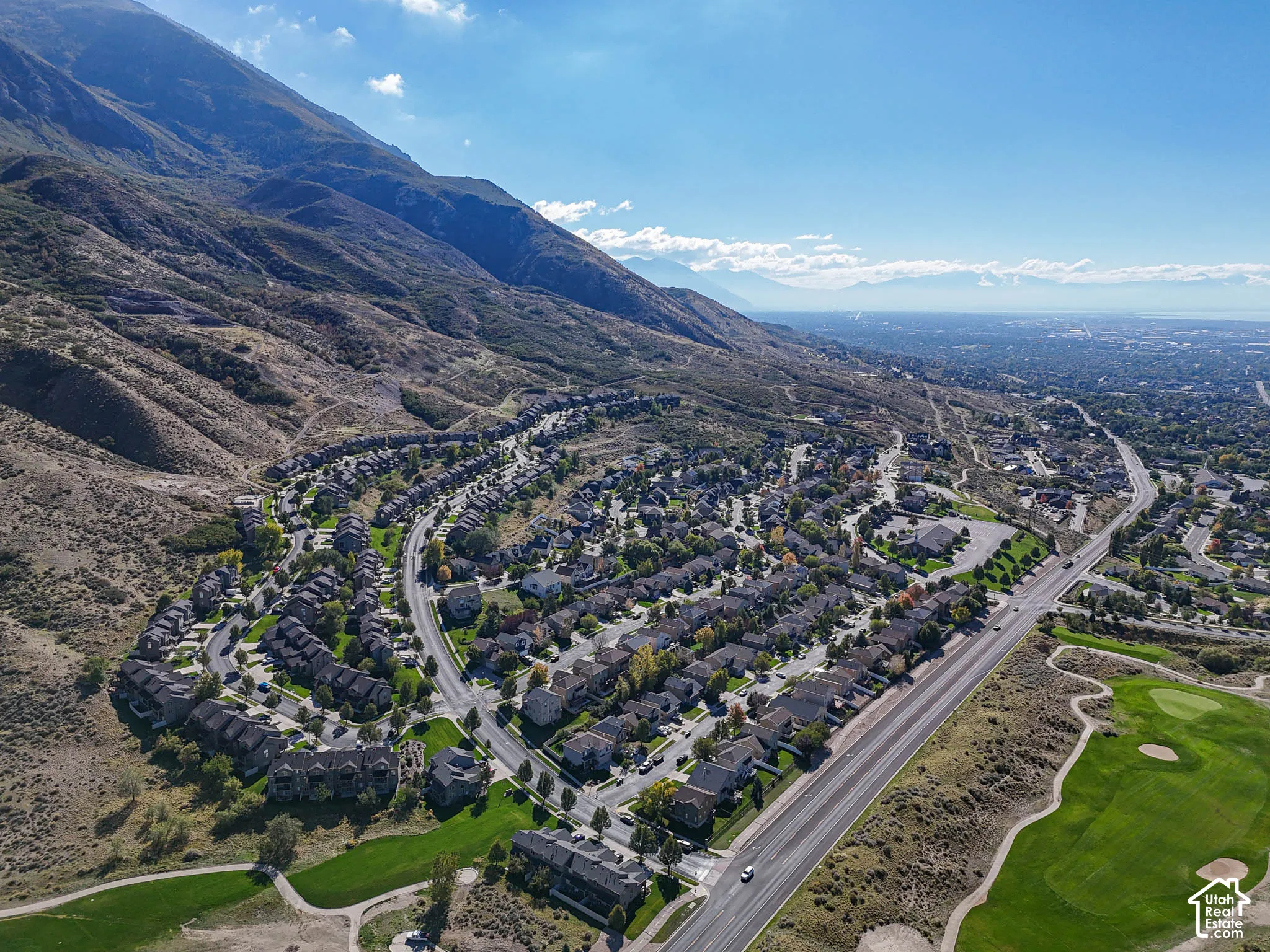 Aerial perspective featuring expansive mountain terrain, established residential streetscapes, and bordering golf course greens
