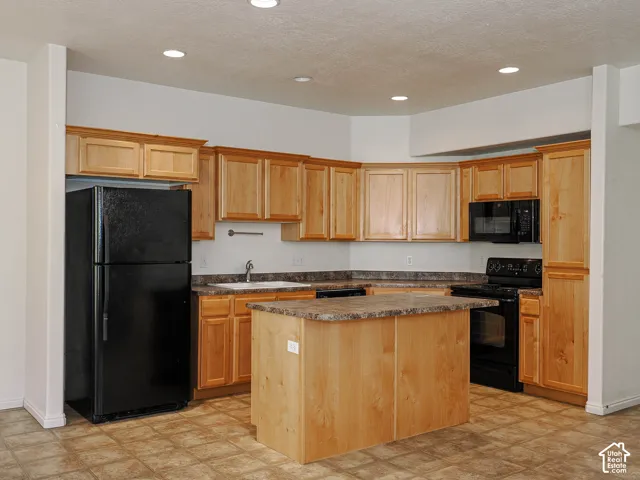 Kitchen featuring light-finish wood cabinetry, a central island with countertop, stone-pattern laminate countertops, and recessed ceiling lighting