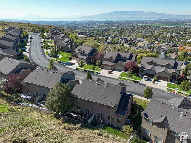 Elevated hillside residential community featuring multi-level dwellings with asphalt shingle roofing, paved roadways, and prominent mountain and valley scenery