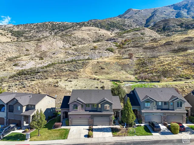 Multi-unit exterior featuring stone and stucco siding, asphalt shingle roofs, multi-car garages, and prominent mountain backdrop