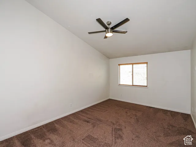 Vaulted ceiling featuring a central brushed-nickel finish ceiling fan with integrated lighting and wall-to-wall carpeting