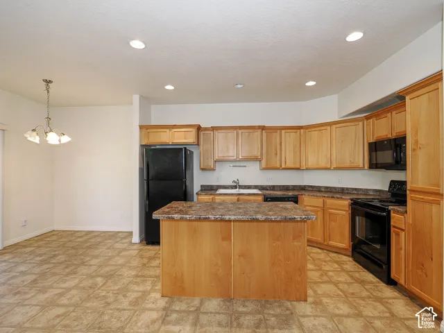 Kitchen featuring natural wood cabinetry, central island, laminate countertops, recessed lighting, and a pendant chandelier