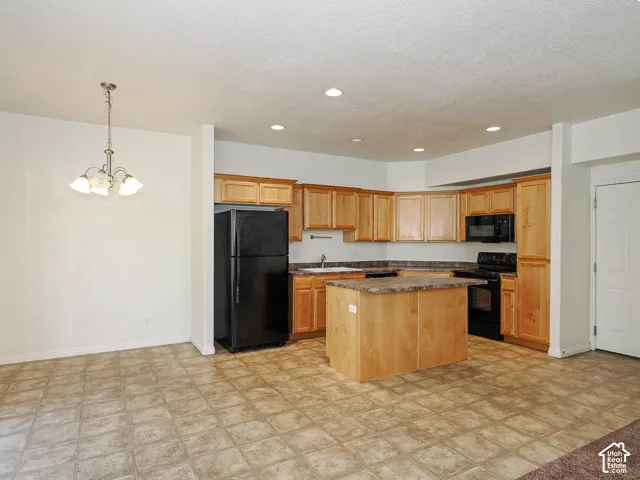 Kitchen featuring light wood cabinetry, center island with laminate countertop, recessed lighting, and built-in appliances