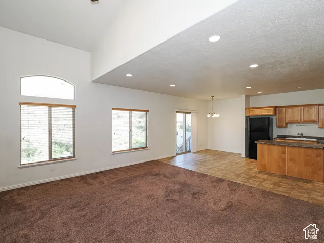 Vaulted ceilings, recessed lighting, arched accent window, wood-finish cabinetry, and kitchen peninsula