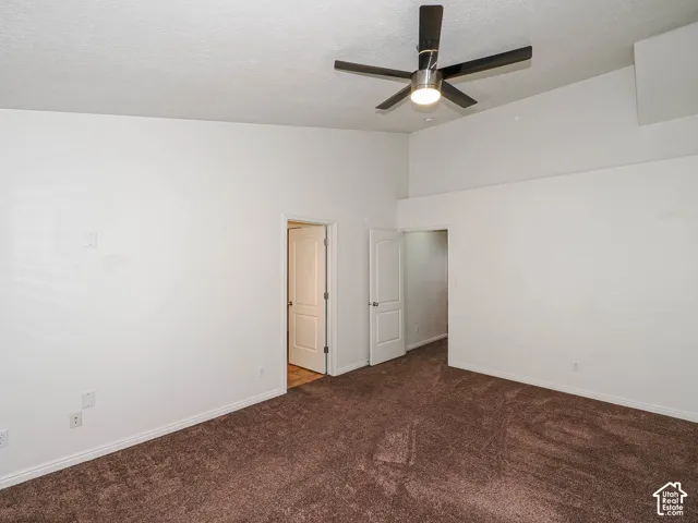 Vaulted ceilings featuring a contemporary ceiling fan with integrated lighting, paired with carpeting and two interior doors
