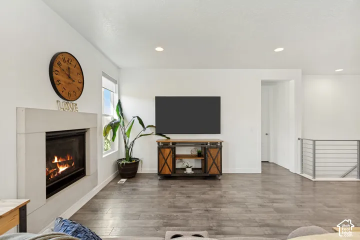 Open-concept living space anchored by a gas fireplace with white surround and shiplap detailing, complemented by a wood-finish media console with X-frame barn doors and shelving