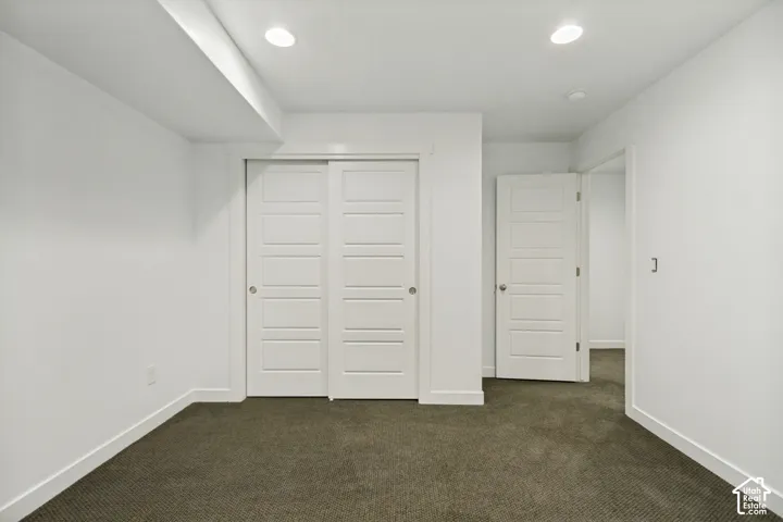 Interior room featuring neutral wall-to-wall carpeting, recessed ceiling lighting, and a sliding-door closet with four-panel wood doors
