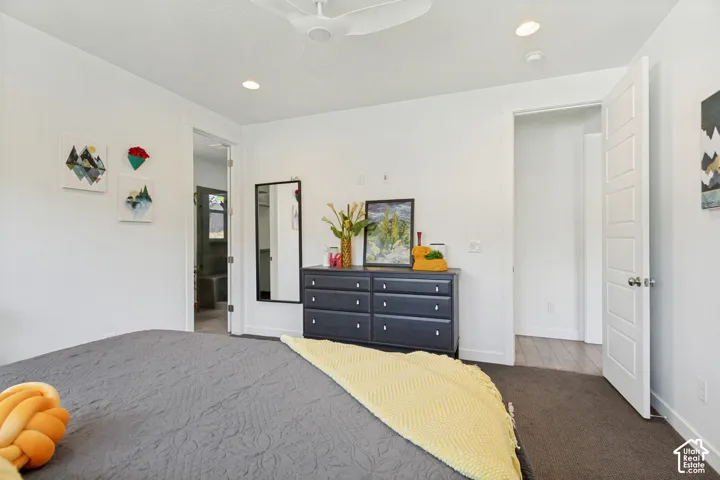 Neutral-toned bedroom featuring recessed lighting, a modern ceiling fan, dark carpeting, and a five-panel interior door