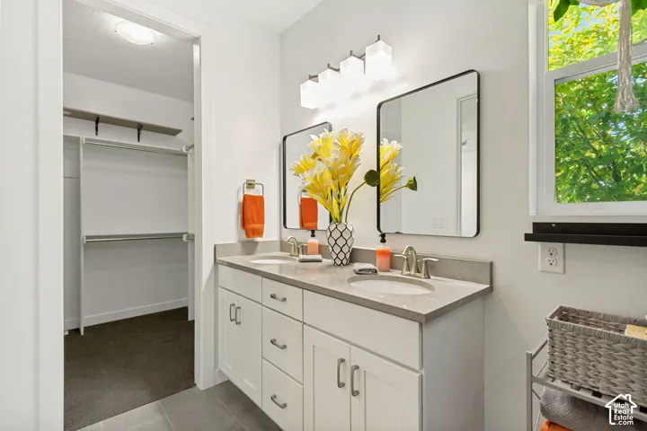 Dual-sink vanity featuring stone-composite countertops, shaker-style cabinetry, framed vanity mirrors, and multi-light wall fixtures