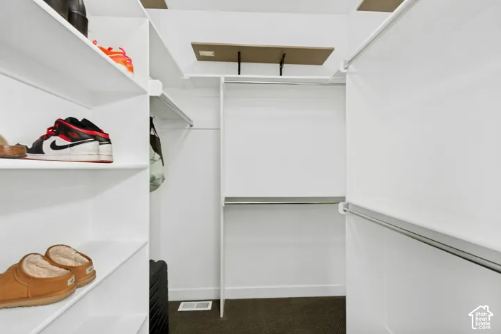 Walk-in closet featuring white built-in shelving, multiple hanging rods, and integrated overhead storage platforms