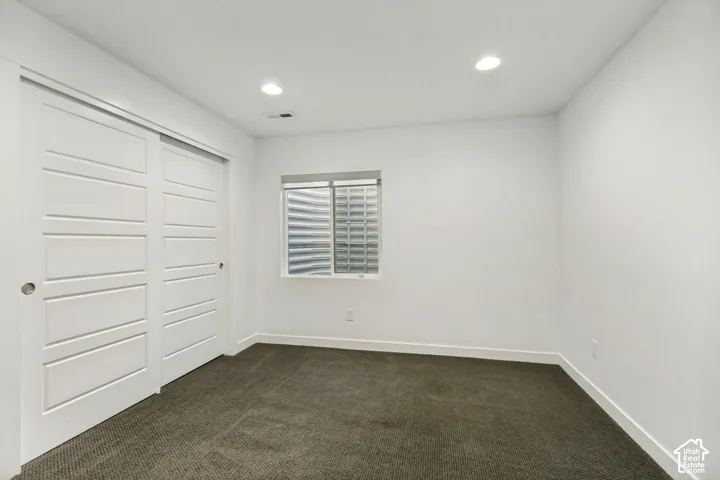 Interior room featuring neutral wall-to-wall carpeting, recessed ceiling lighting, and a sliding closet door with a multi-panel design