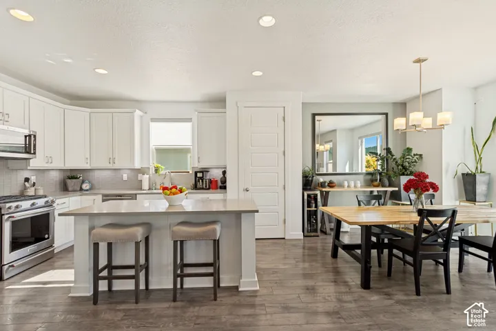 Kitchen featuring shaker-style cabinetry, stone countertops, central island, stainless steel appliances, and wood-finish flooring