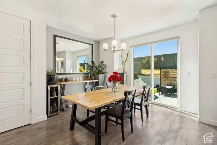 Dining space featuring wood-finish flooring, a multi-light brushed-nickel chandelier, a large wall-mounted mirror, and sliding glass doors leading to an exterior deck