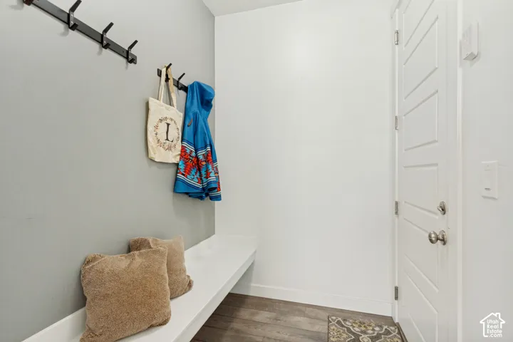Built-in white bench seating, two matte black wall-mounted coat hook racks, and wood-finish flooring