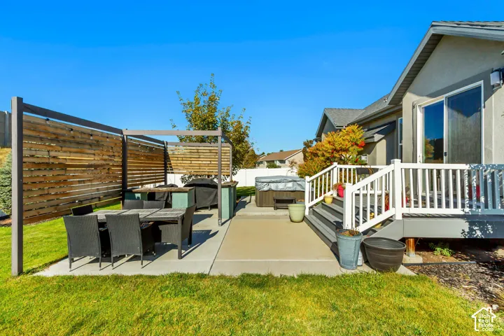 Rear exterior space featuring a composite deck with white railings, a concrete patio, a wood-slat privacy screen, and a built-in outdoor counter