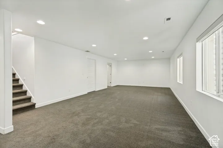 Open-concept interior featuring neutral wall-to-wall carpeting, recessed ceiling lighting, and multi-pane windows