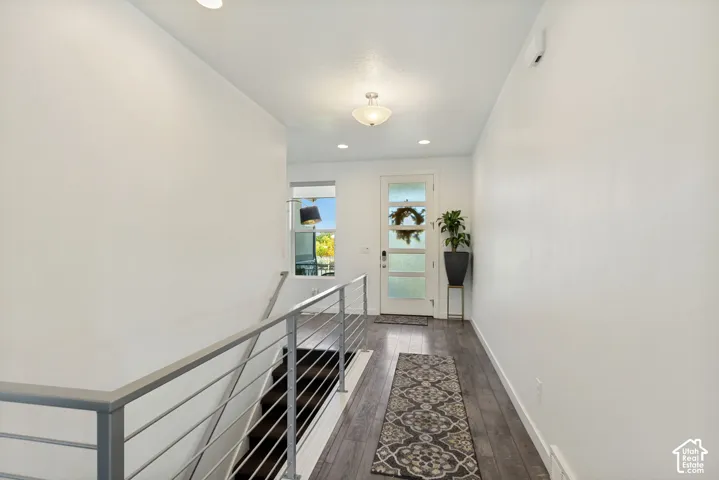 Entryway featuring wood-finish flooring, a glass-panel front door, recessed lighting, and a metal horizontal-bar railing