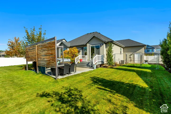 Backyard featuring a concrete patio, elevated deck with railings, custom wood privacy screen, and white vinyl perimeter fencing