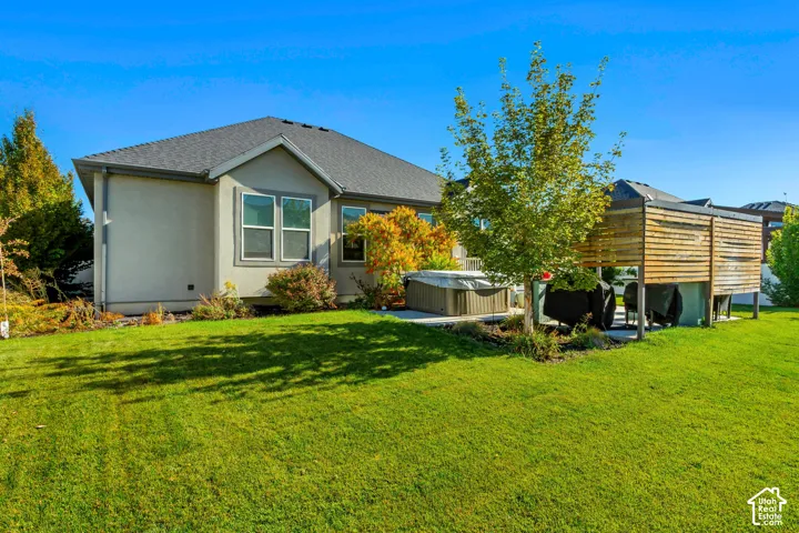 Backyard featuring a manicured lawn, concrete patio, built-in hot tub, and a wooden privacy screen