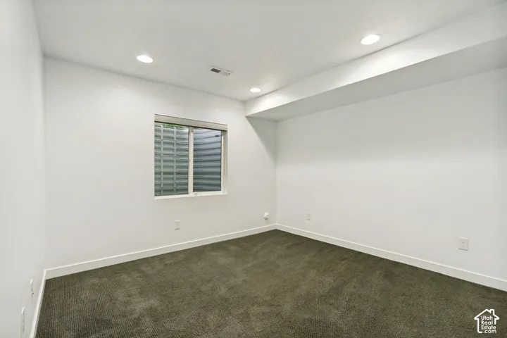 Room featuring neutral wall finishes, recessed lighting, carpeted flooring, and a window with a corrugated metal window well