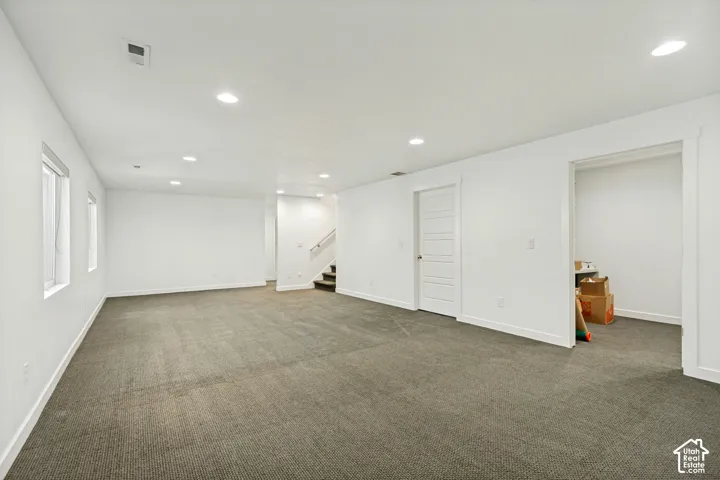 Open-concept interior featuring neutral wall-to-wall carpeting, recessed ceiling lighting, a multi-panel interior door, and dual windows