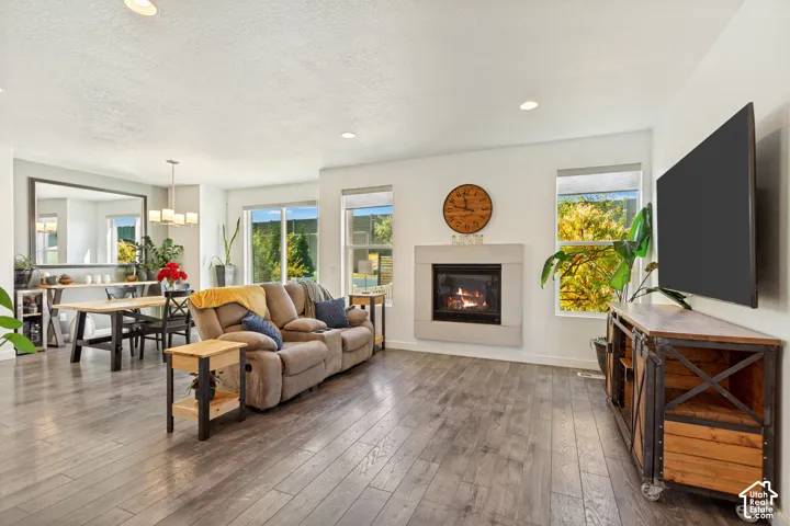 Living area featuring wood-finish flooring, recessed lighting, and a fireplace with a light-tone stone surround