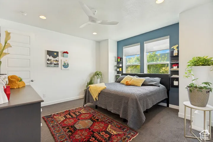 Bedroom featuring neutral carpeting, recessed lighting, a modern three-blade ceiling fan, dual windows, and a built-in recessed shelving unit