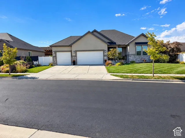 Single-story residence featuring a stone and stucco facade, a three-car garage, and a manicured front lawn