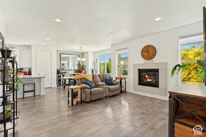 Open-concept living space featuring wood-finish flooring, recessed lighting, and a fireplace with a concrete-finish surround
