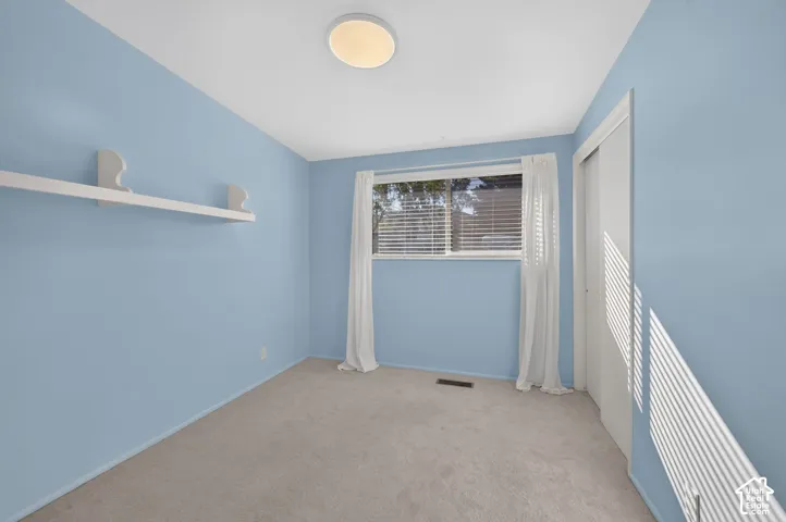Neutral-toned carpeting, wall-mounted shelving unit, flush-mount ceiling light fixture, and sliding closet doors