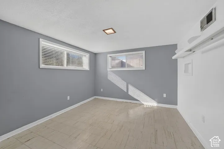 Neutral-toned room featuring tile flooring, dual slider windows with horizontal blinds, and a built-in recessed ceiling light