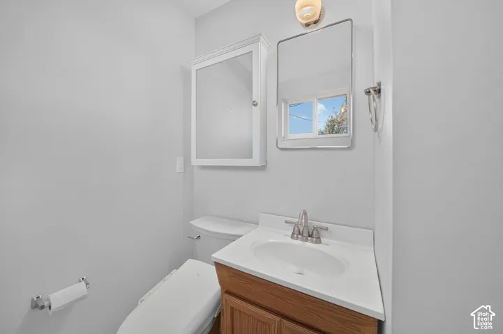 Wood-finish vanity cabinet, integrated sink, brushed metal dual-handle faucet, wall-mounted medicine cabinet, and rounded-corner mirror