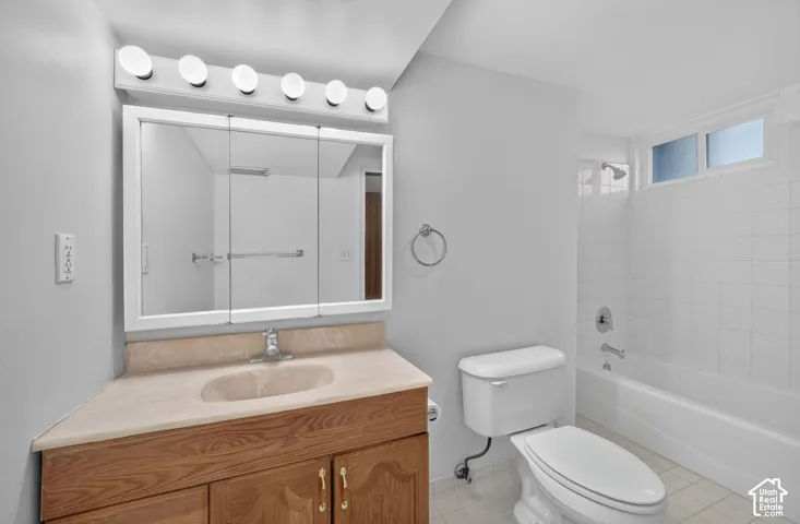 Bathroom featuring a wood vanity with a solid-surface countertop, integrated basin, triple-panel medicine cabinet, and a tiled tub-shower combination