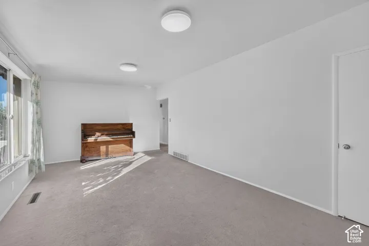 Neutral-toned carpeting, dual flush-mount ceiling light fixtures, and a multi-pane window