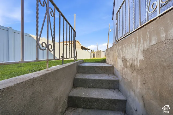 Concrete stairwell featuring metal railings and a solid vinyl perimeter fence