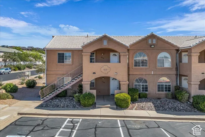 Stucco exterior featuring arched windows, light-toned tile roofing, and metal exterior staircase