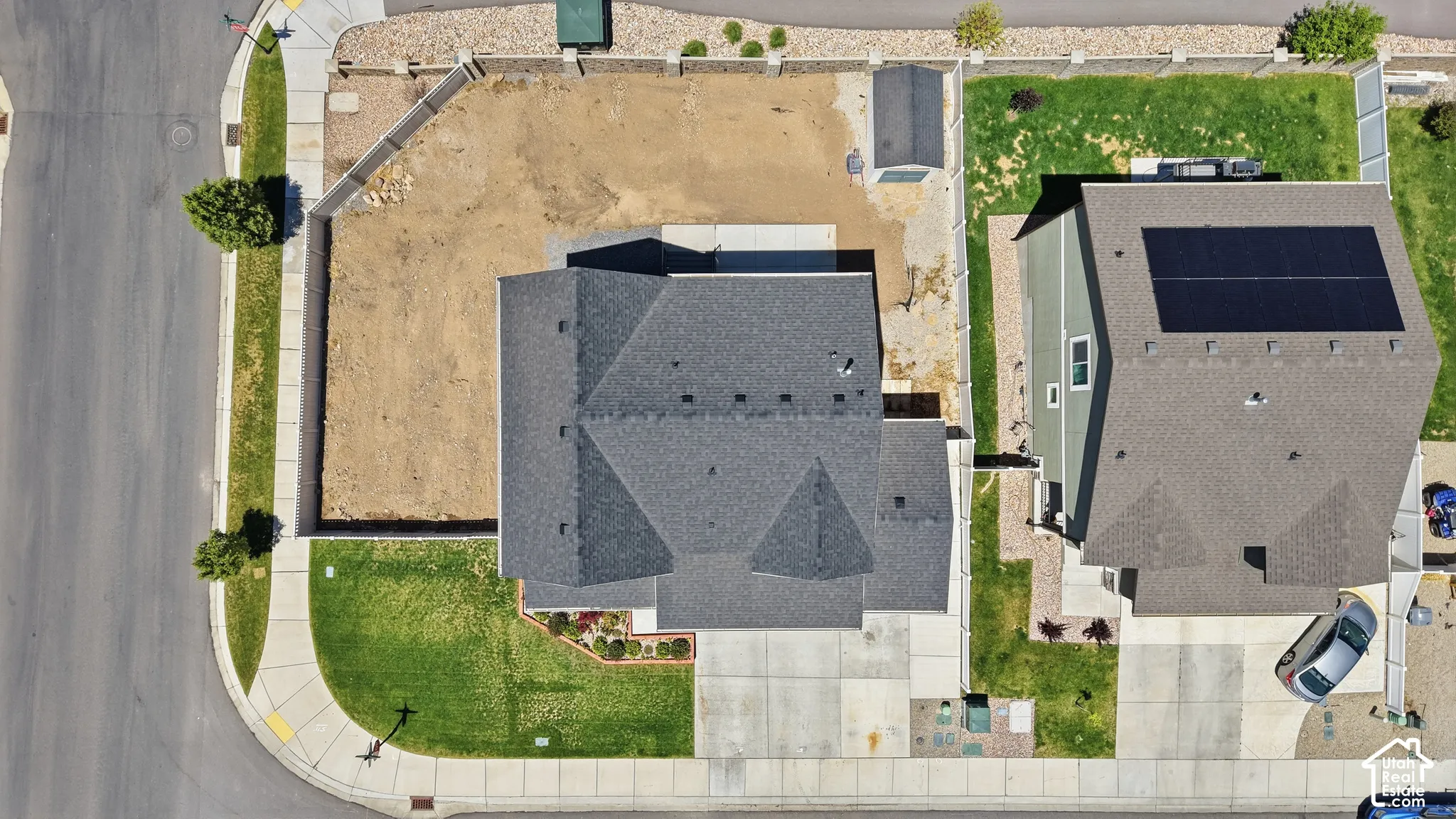 Corner lot with a fenced yard, paved concrete driveway, and asphalt shingle roofing