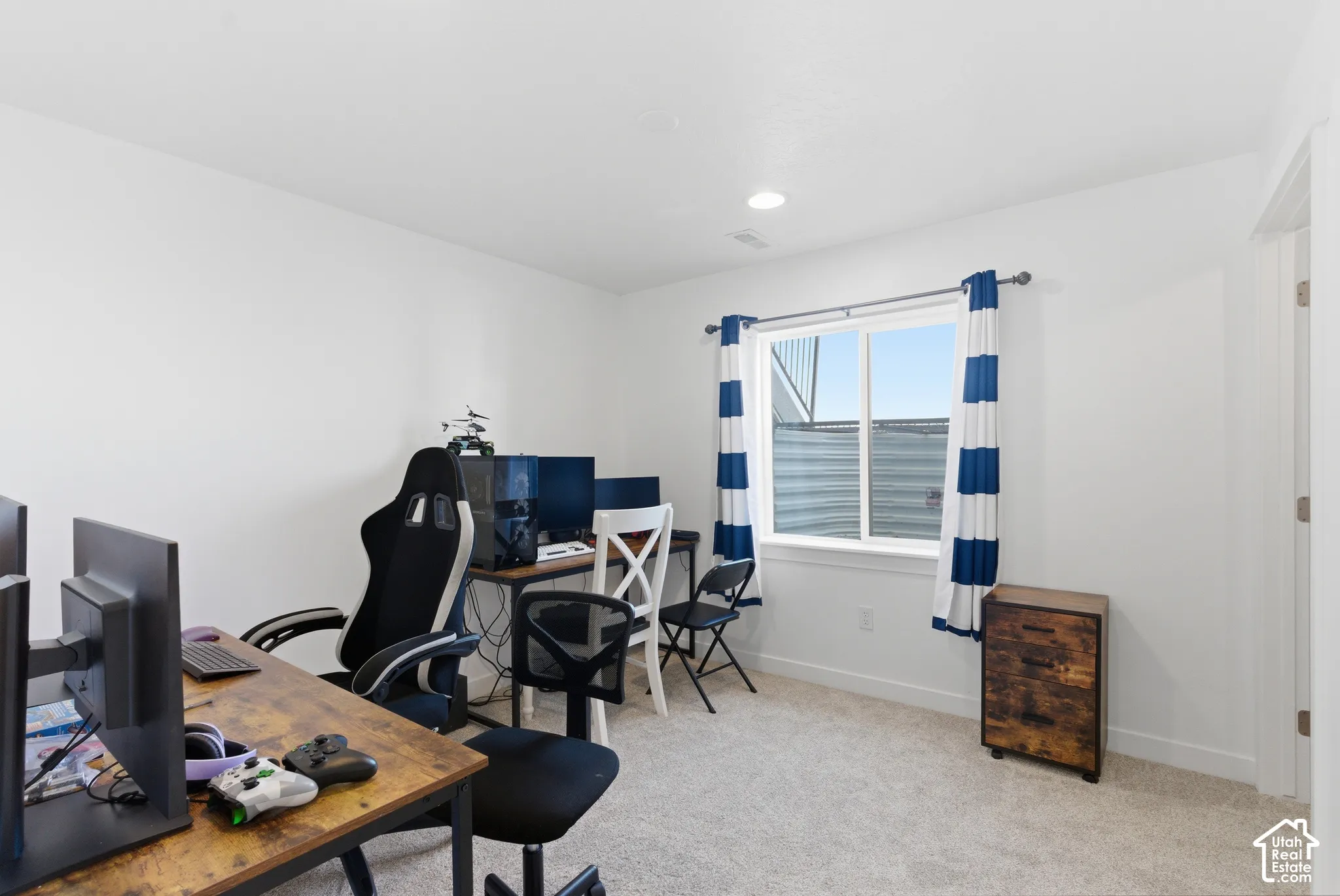 Room featuring neutral-toned carpeting, crisp white walls, and a sliding window with an integrated egress well
