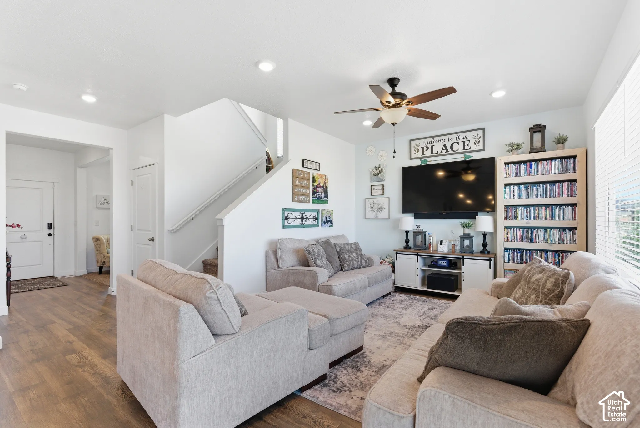 Living area featuring wood-finish flooring, recessed lighting, a ceiling fan, and a built-in bookshelf
