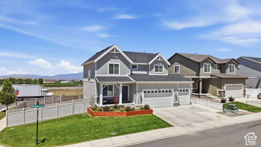 Two-story residence featuring a board-and-batten siding exterior, asphalt shingle roof, three-car garage, and a raised concrete porch with wood-accented planter boxes