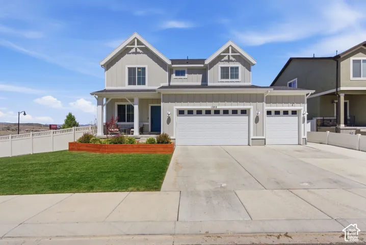 Two-story exterior with board and batten siding, dual front-facing gables, a three-car garage, and a raised wooden garden bed