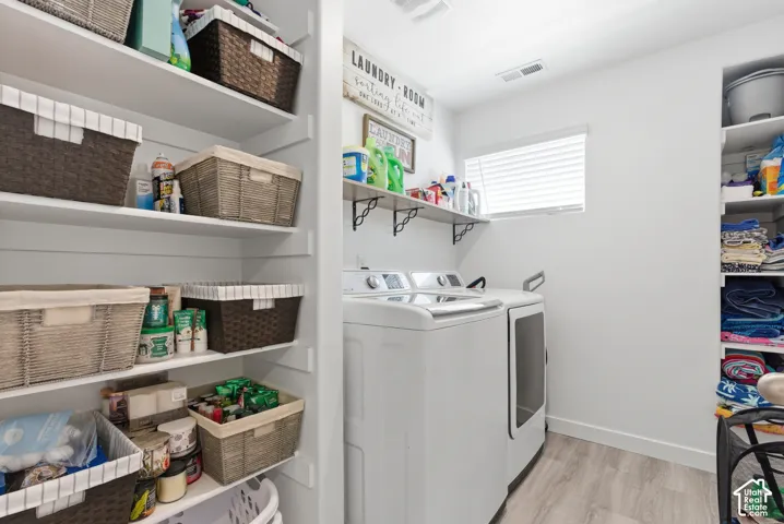 Laundry area featuring extensive built-in shelving, wood-finish flooring, a wall-mounted display shelf with decorative brackets, and a horizontal window with blinds