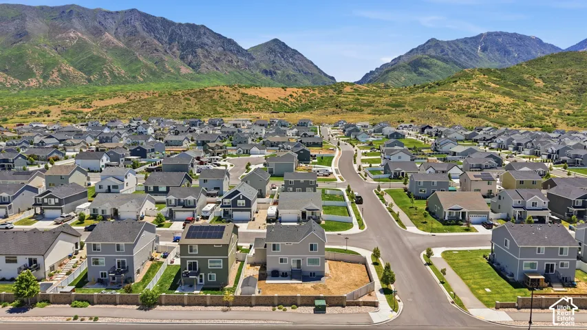 Aerial perspective showcasing multi-level residential structures, integrated solar panels, fenced perimeter hardscaping, and a prominent mountain backdrop