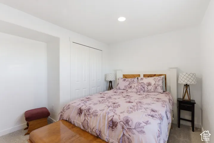 Neutral-toned carpeted flooring, white walls, built-in closet with double doors, and recessed ceiling lighting