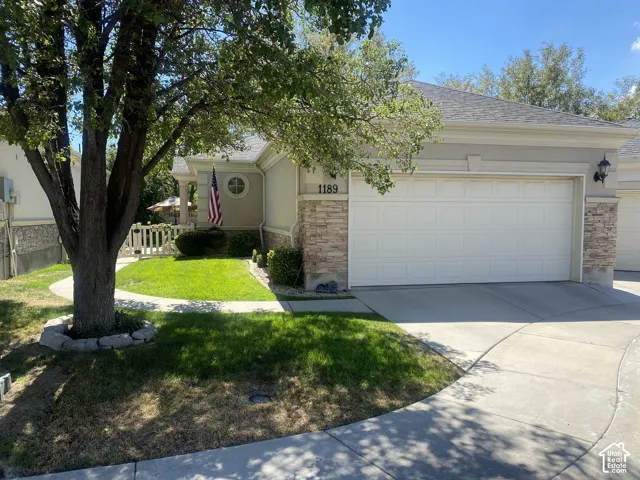 Exterior featuring a neutral stucco finish, stone veneer accents, an attached two-car garage, a concrete driveway, and an arched entryway with a circular accent window